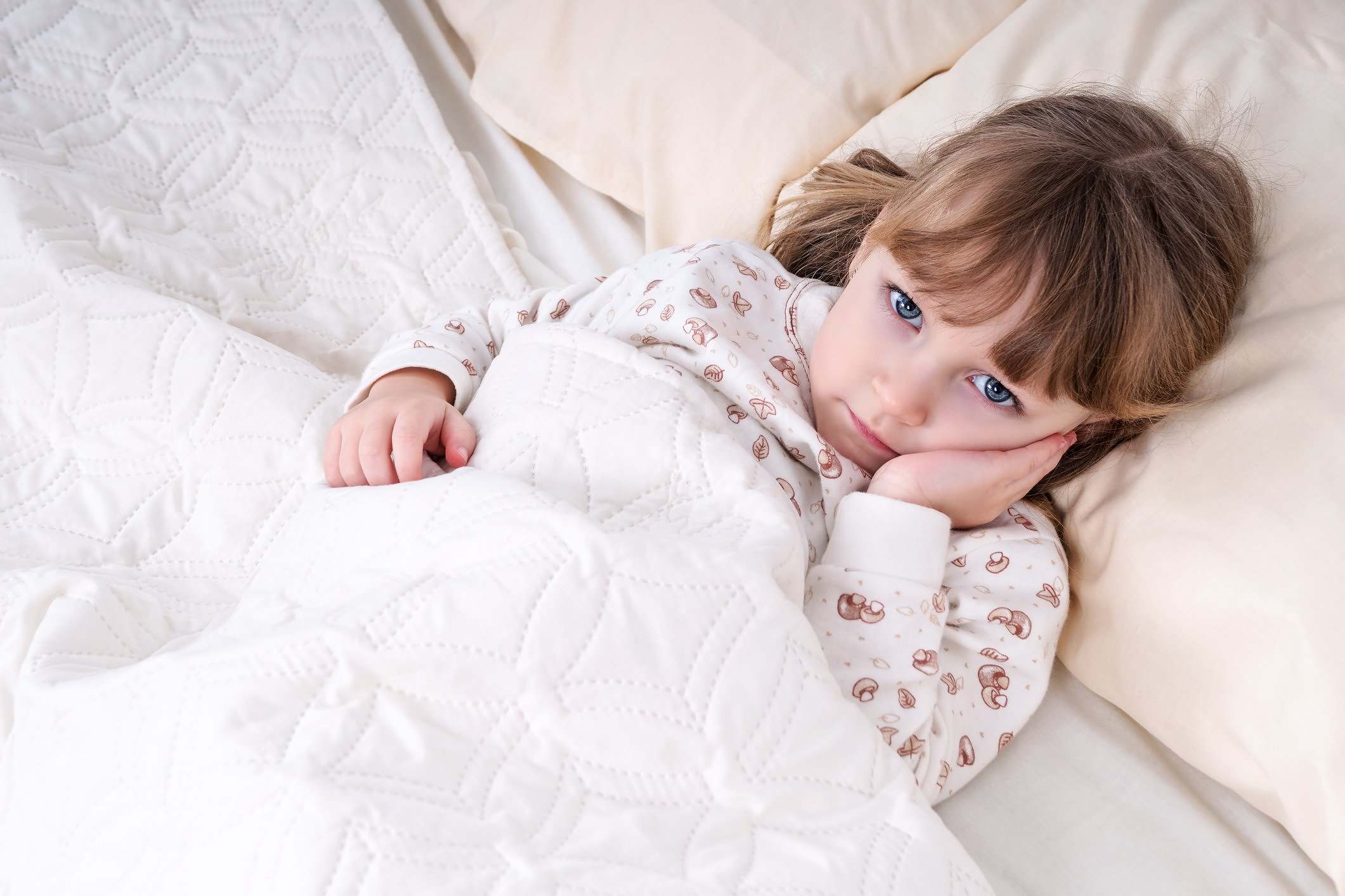 Child In Bed With Hand On Cheek Little beautiful girl lying in bed and holding her cheek with a sick tooth
